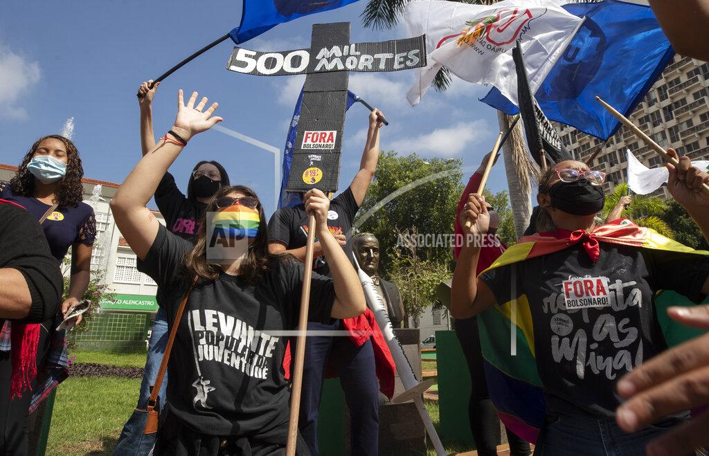 Andre Penner A woman, wearing a protective face mask, holds a sign in the shape of a cross with a message that reads in Portuguese;"500 k deaths", during a protest against Brazilian President Jair Bolsonaro and his handling of the pandemic and economic policies protesters say harm the interests of the poor and working class, in Cuiaba, Brazil, Saturday, June 19, 2021. Brazil is approaching an official COVID-19 death toll of 500,000 — second-highest in the world. (AP Photo/Andre Penner)