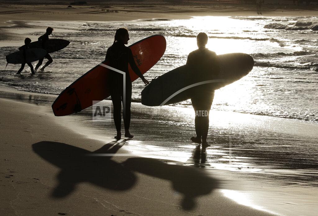 Rick Rycroft Surfers prepare to enter the water at Bondi Beach in Sydney, Tuesday, April 28, 2020, as coranavirus pandemic restrictions are eased. The beach is open to swimmers and surfers to exercise only. (AP Photo/Rick Rycroft)