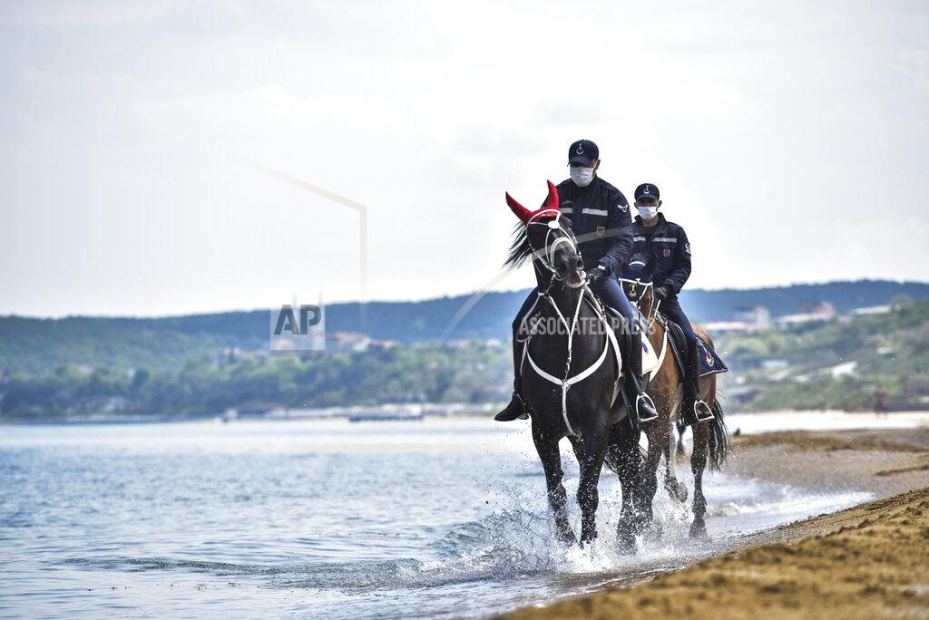 Members of the Equestrian Gendarmerie Units, which normally serve to protect the Topkapı Palace, wearing face masks for protection against the coronavirus, as they patrol the beaches in Sariyer outside Istanbul, Saturday, May 2, 2020. The equestrian unit is used to patrol the beach area to enforce the curfew measures, restricting people from walking around or swimming. (Ibrahim Mase/DHA via AP)
