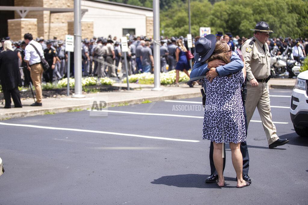 Silas Walker Law enforcement officer embraces a woman in the making lot after the funeral service for Floyd County Deputy William Petry at the Mountain Arts Center in Prestonsburg, Ky., Tuesday, July 5, 2022. Petry and two Prestonsburg city police officers were killed while serving a warrant at a home in the county. (Silas Walker/Lexington Herald-Leader via AP)