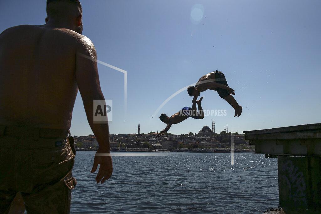 Emrah Gurel Backdropped by the historical Suleymaniye mosque youths jump from the Galata Bridge into the Golden Horn leading to the Bosphorus Strait separating Europe and Asia, in Istanbul, Friday, May 14, 2021. Turkey is in the final days of a full coronavirus lockdown and the government has ordered people to stay home and businesses to close amid a huge surge in new daily infections. But millions of workers are exempt and so are foreign tourists. Turkey is courting international tourists during an economic downturn and needs the foreign currencies that tourism brings to help the economy as the Turkish lira continues to sink. (AP Photo/Emrah Gurel)
