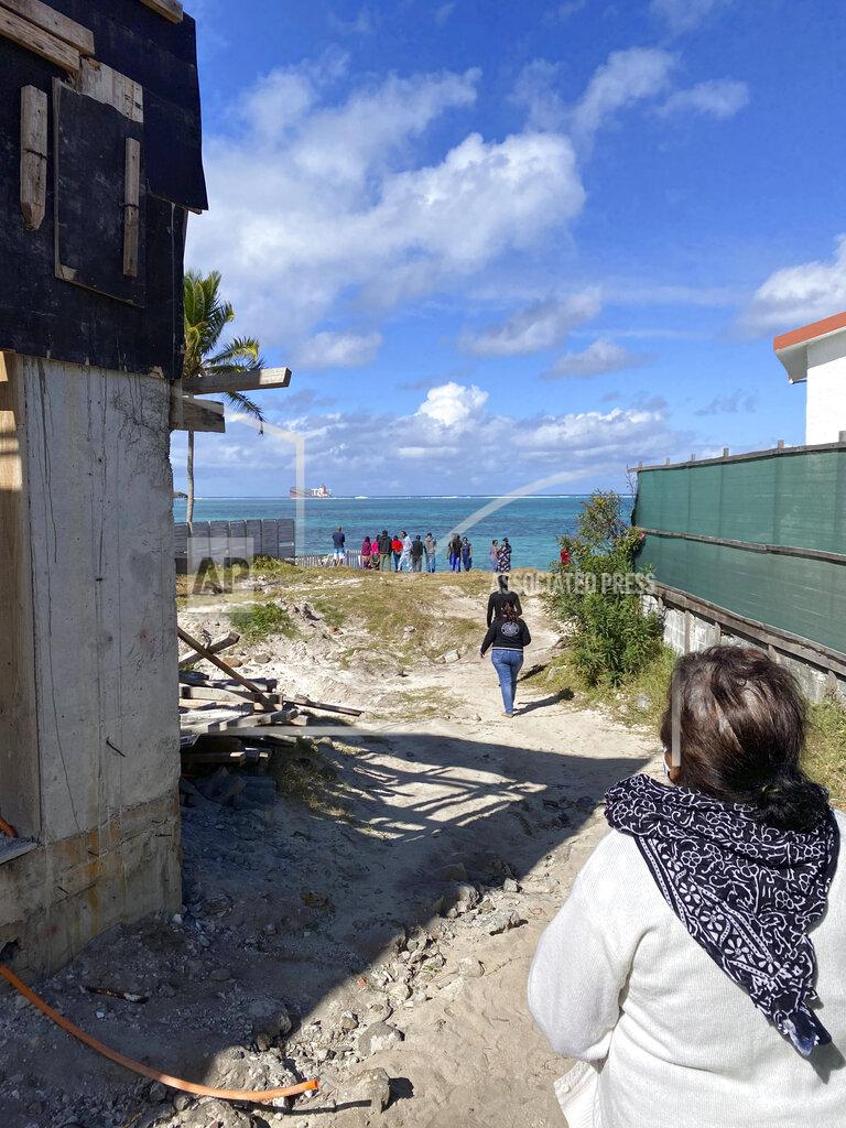 Uncredited In this photo provided by Grégoire Rouxel people walk towards the coast to see a ship that ran aground off shore that is leaking fuel, Friday, Aug. 7, 2020, in Mauritius. The Indian Ocean island of Mauritius has declared a "state of environmental emergency" after a Japanese-owned ship that ran aground offshore days ago began spilling tons of fuel. Prime Minister Pravind Jugnauth announced the development late Friday, Aug. 7, as satellite images showed a dark slick spreading near environmental areas the government called "very sensitive." (@gregrouxel via AP)
