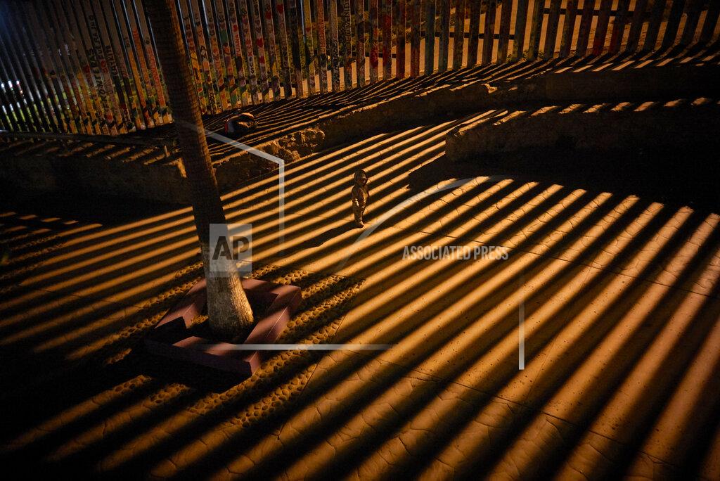 Gregory Bull FILE- A boy plays as floodlights from the United States filter through the bars of the newly replaced border wall Friday, Jan. 11, 2019, in Tijuana, Mexico. Top Trump administration officials will visit South Texas five days before Election Day to announce they have completed 400 miles of U.S.-Mexico border wall, attempting to show progress on perhaps the president's best-known campaign promise four years ago. But most of the wall went up in areas that already had smaller barriers. (AP Photo/Gregory Bull)