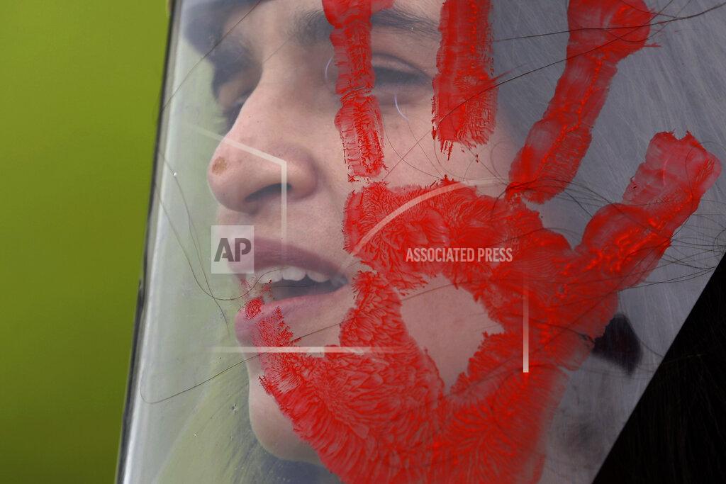 A demonstrator wears a face shield with a red handprint, mimicking blood, to protest Brazilian President Jair Bolsonaro's handling of the deadly coronavirus pandemic in Brasilia, Brazil, Wednesday, Dec. 23, 2020. Protesters also called for the immediate start of COVID-19 vaccinations. (AP Photo/Eraldo Peres)