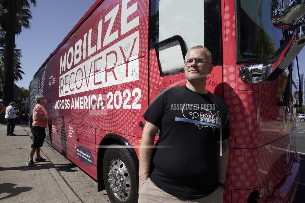 Rich Pedroncelli Ryan Hampton, founder of the Voices Project, poses outside the 2022 Mobile Recovery National Bus during a stop in Sacramento, Calif., Wednesday, Sept. 7, 2022. Across the country, people in recovery and relatives of those killed by opioid overdoses are pressing for roles in determining how billions in opioid settlement money will be used. That push is one of the missions of the monthlong nationwide bus tour. (AP Photo/Rich Pedroncelli)