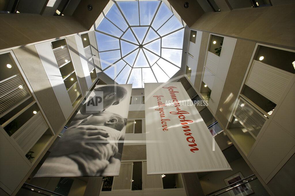 FILE - In this July 30, 2013, file photo, large banners hang in an atrium at the headquarters of Johnson & Johnson in New Brunswick, N.J. Johnson & Johnson is beginning a huge final-stage study Wednesday, Sept. 23, 2020, to try to prove if a single-dose COVID-19 vaccine can protect against the virus. (AP Photo/Mel Evans, File)