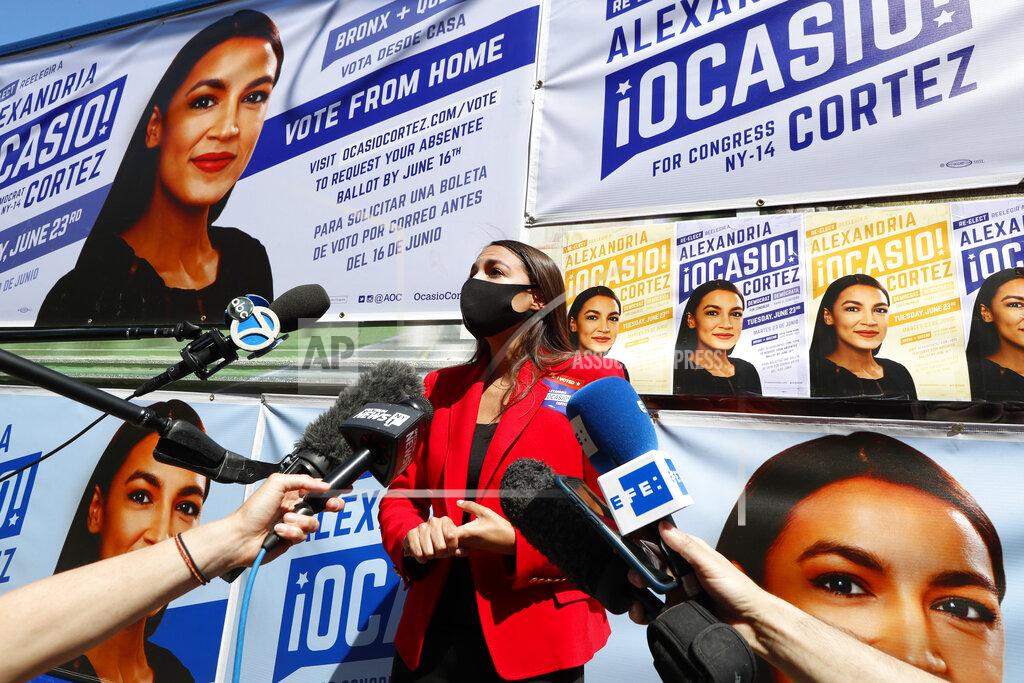 Kathy Willens U.S. Rep. Alexandria Ocasio-Cortez, D, New York, center, speaks to members of the media while standing beside a truck plastered with campaign posters after greeting voters in Astoria, Queens, Tuesday, June 23, 2020, on primary election day in New York. (AP Photo/Kathy Willens)