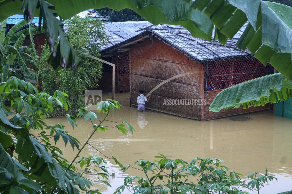 Shafiqur Rahman A Rohingya refugee walks through flood water following heavy rains at the Rohingya refugee camp in Kutupalong, Bangladesh, Wednesday, July 28, 2021. Days of heavy rains have brought thousands of shelters in various Rohingya refugee camps in Southern Bangladesh under water, rendering thousands of refugees homeless. (AP Photo/ Shafiqur Rahman)
