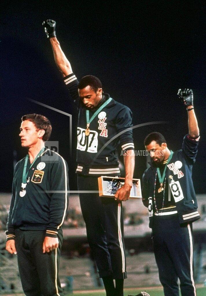 FILE - In this Oct. 16, 1968, file photo, U.S. athletes Tommie Smith, center, and John Carlos extend gloved hands skyward in racial protest during the playing of national anthem after Smith received the gold and Carlos the bronze for the 200 meter run at the Summer Olympic Games in Mexico City. Australian silver medalist Peter Norman is at left. The U.S. Olympic and Paralympic Committee will allow raised fists and kneeling during the national anthem at upcoming Olympic trials. The USOPC released a nine-page document to offer guidance about the sort of “racial and social demonstrations” that will and won't be allowed by the hundreds of athletes who will compete for spots on the U.S. team in various sports. (AP Photo/File)