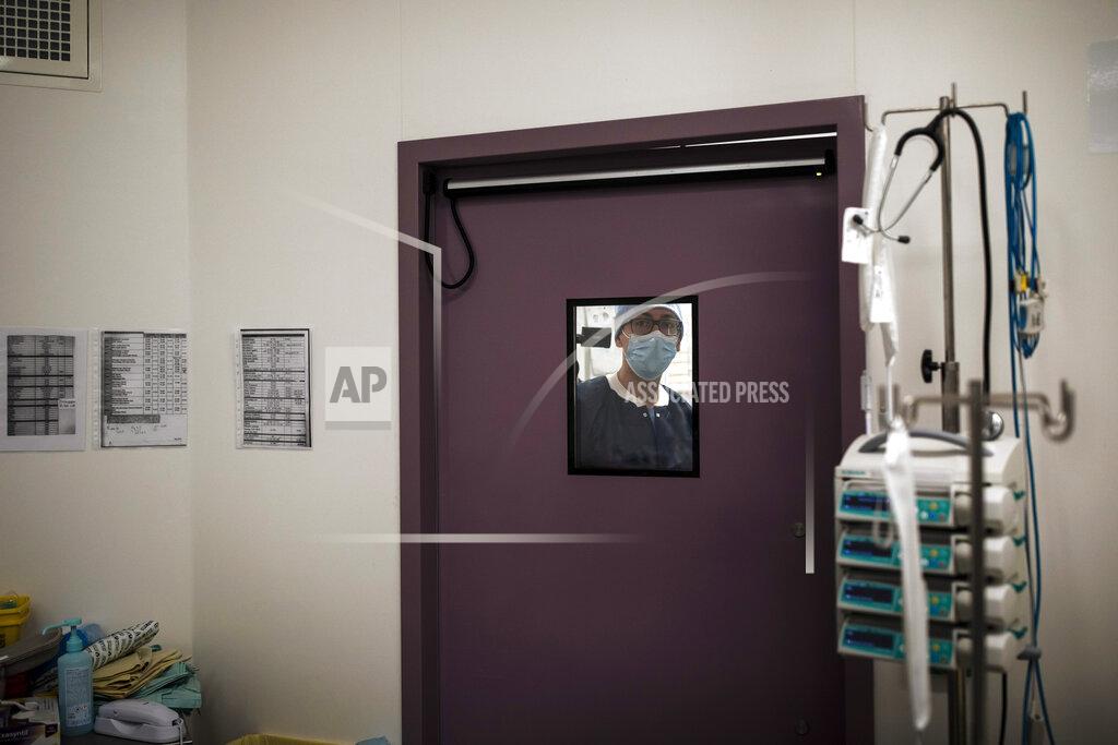 Lewis Joly Nurse Guillaume Meuleman is seen through the window of an operating room at Bichat Hospital, AP-HP, in Paris, Thursday, April 22, 2021. France still had nearly 6,000 critically ill patients in ICUs this week as the government embarked on the perilous process of gingerly easing the country out of its latest lockdown, too prematurely for those on pandemic frontlines in hospitals. President Emmanuel Macron's decision to reopen elementary schools on Monday and allow people to move about more freely again in May, even though ICU numbers have remained stubbornly higher than at any point since the pandemic's catastrophic first wave, marks another shift in multiple European capitals away from prioritizing hospitals. In France, Greece and elsewhere, the cursor is moving back toward other economic, social and educational imperatives. (AP Photo/Lewis Joly)