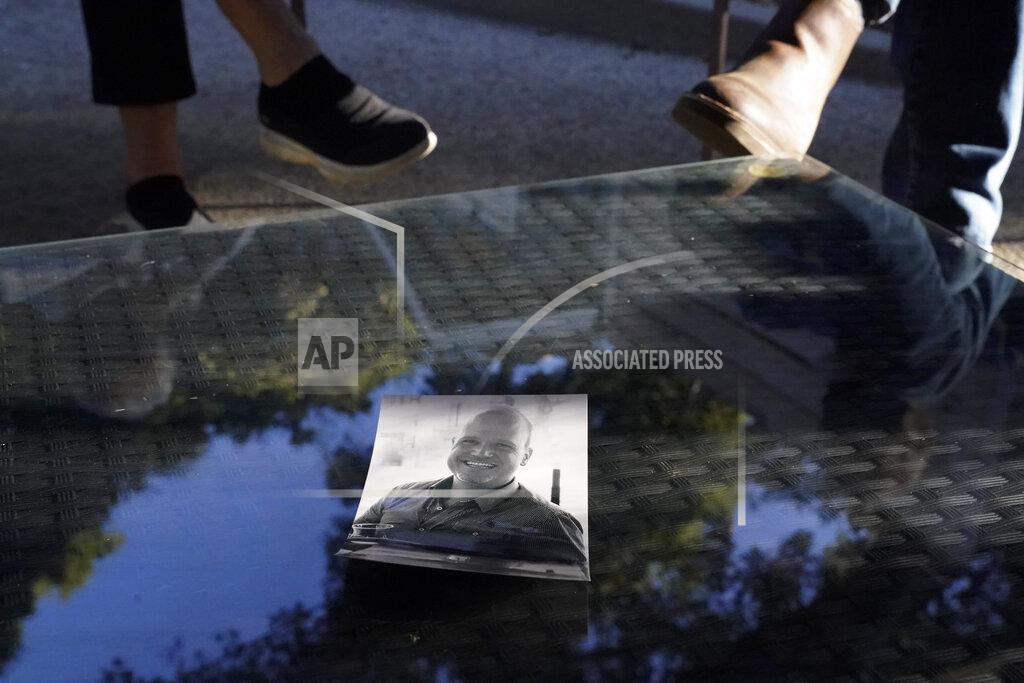 Ashley Landis A photo of Charles McIlvain, center, lays on a table between his parents, Kathleen McIlvain, left, and Clark McIlvain, at their home on Thursday, Dec. 3, 2020, in Woodland Hills, Calif. Charles McIlvain was one of 34 people killed when dive boat Conception caught fire and sank off the coast of California on Sept. 2, 2019. (AP Photo/Ashley Landis)