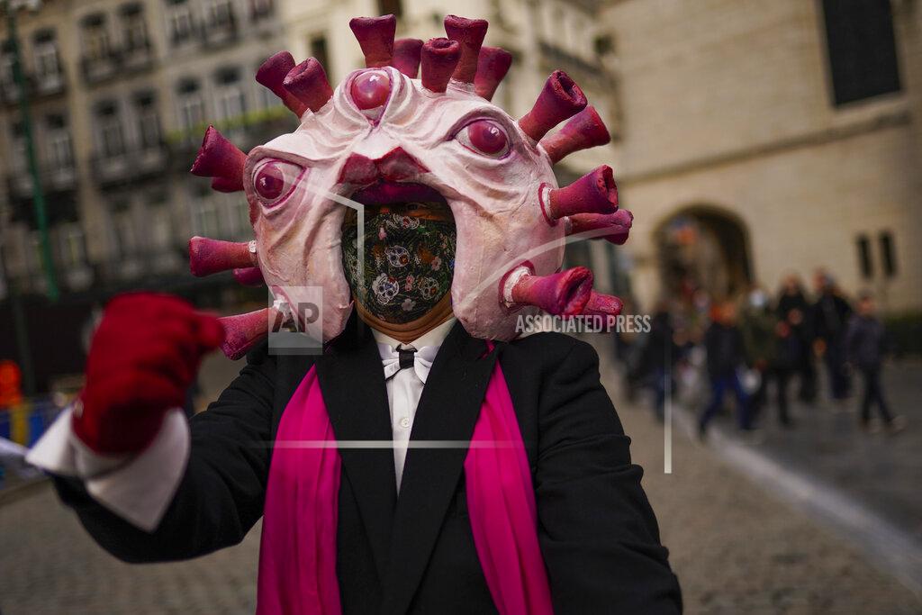 Francisco Seco An actor, dressed up depicting a coronavirus, gestures to passers-by during a street performance promoting anti COVID-19 security measures in downtown Brussels, Thursday, Dec. 31, 2020. (AP Photo/Francisco Seco)