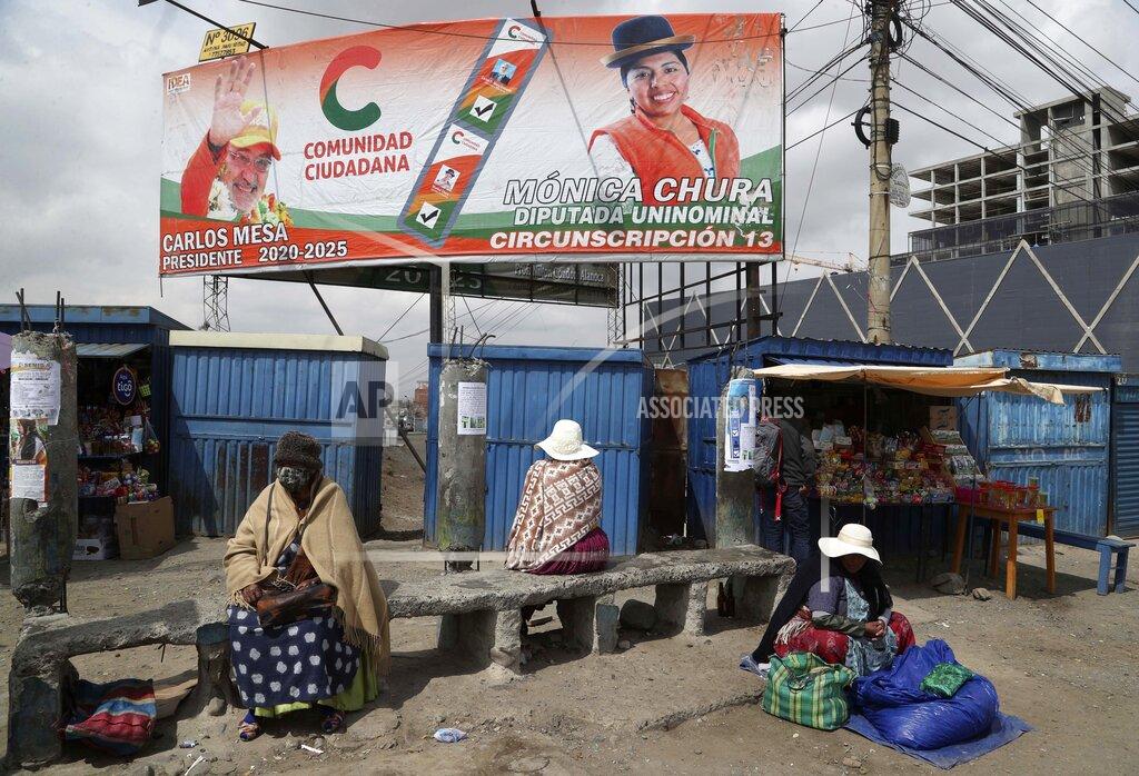 Martin Mejia A billboard promoting presidential candidate Carlos Mesa of the Citizen Community political party towers over a trio of women in Rio Seco, Bolivia, Saturday, Oct. 17, 2020. Sunday's presidential election gives Bolivians a chance for a political reset as they struggle with the dramatic costs of the COVID-19 pandemic. (AP Photo/Martin Mejia)