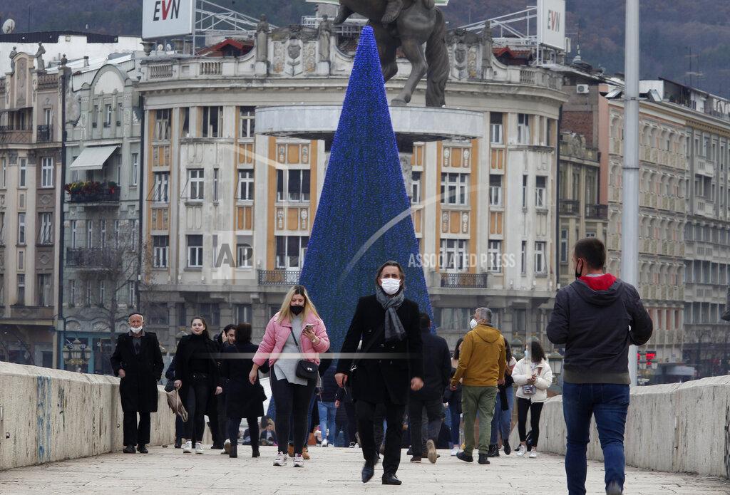 Boris Grdanoski In this picture taken on Tuesday, Dec. 29, 2020, people wearing face masks walk across a bridge in downtown Skopje, North Macedonia. When thousands of people across the European Union simultaneously began rolling up their sleeves last month to get a coronavirus vaccination shot, one corner of the continent was left behind, feeling isolated and abandoned: the Balkans. (AP Photo/Boris Grdanoski)