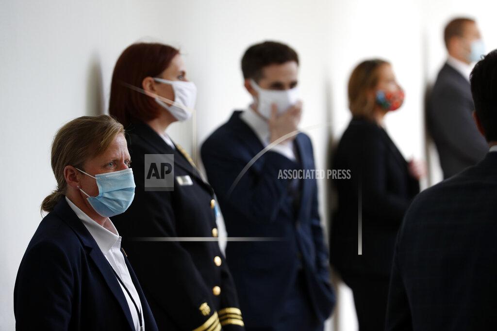 A member of the U.S. Secret Service, front, stands at her post wearing a mask as other staff member social distance wearing masks, before President Donald Trump speaks about the coronavirus during a press briefing in the Rose Garden of the White House, Monday, May 11, 2020, in Washington. (AP Photo/Alex Brandon)