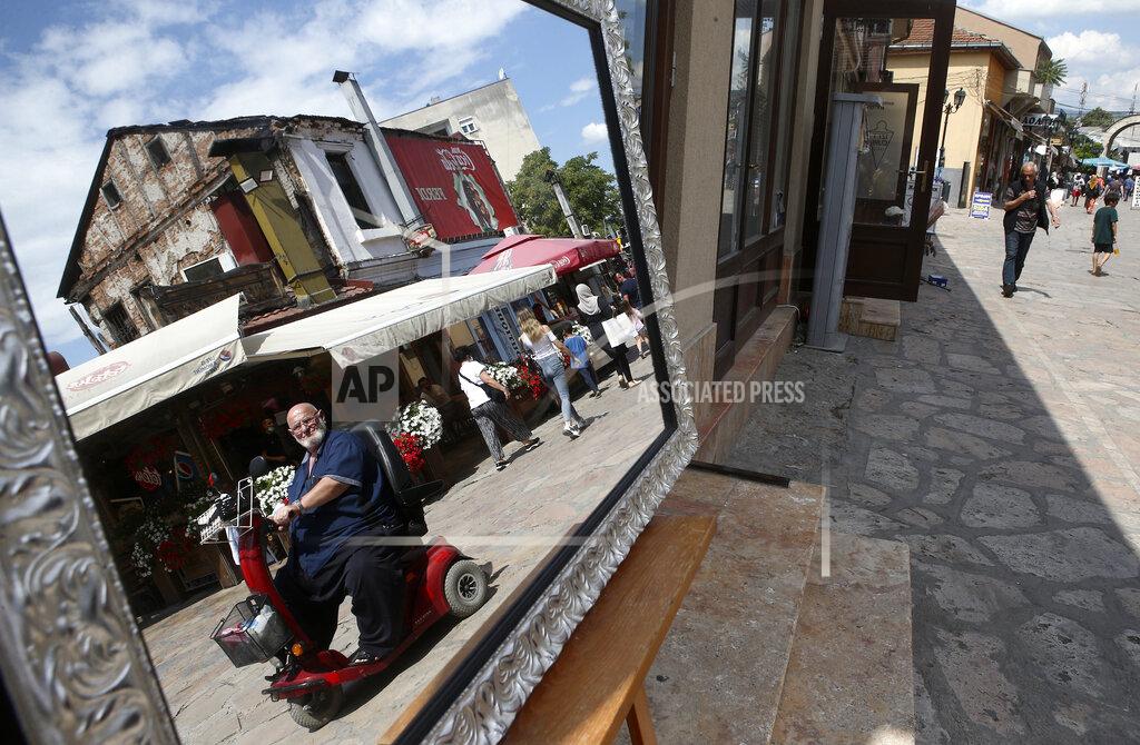 Boris Grdanoski A reflection of a man riding an electric vehicle is pictured in a displayed mirror in the Old Bazaar in Skopje, North Macedonia on Thursday, July 16, 2020. The pro-Western SDSM party in North Macedonia is poised to try to form a coalition government following a narrow election victory. (AP Photo/Boris Grdanoski)