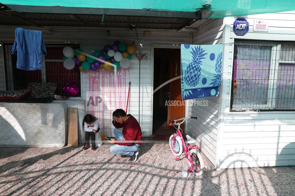 Esteban Felix Jose Collantes kneels next to his daughter Kehity as she pauses over the loss of her mother, Silvia Cano, who died of COVID-19 two months prior, as the five-year-old pauses from playing in the patio of their home where they live with Jose's sister in Santiago Chile, Thursday, Aug. 6, 2020. The father and daughter are of the thousands of people who have lost loved ones to COVID-19 in Chile, one of the countries in Latin America hardest hit by the virus. (AP Photo/Esteban Felix)
