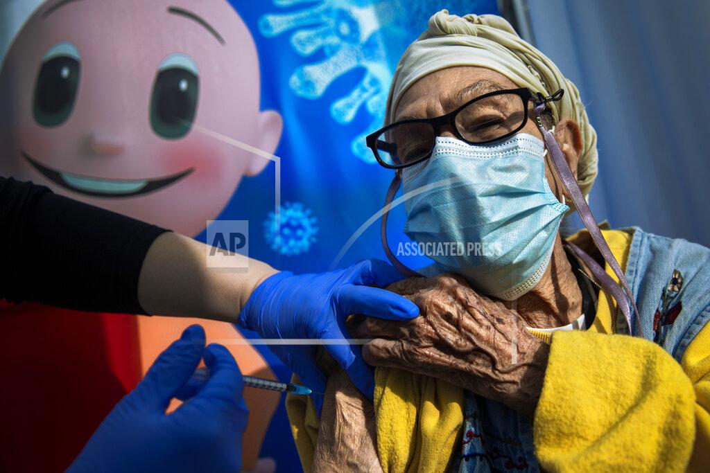 Oded Balilty FILE - In this Tuesday, Jan. 5, 2021. file photo, a woman receives a coronavirus vaccine from medical staff at a COVID-19 vaccination center in Tel Aviv, Israel. Israel's Prime Minister Naftali Bennett announced the country will offer a coronavirus booster to people over 60 who have already been vaccinated. The campaign makes Israel the first country to offer a third dose of a Western vaccine to its citizens on a wide scale. (AP Photo/Oded Balilty, File)