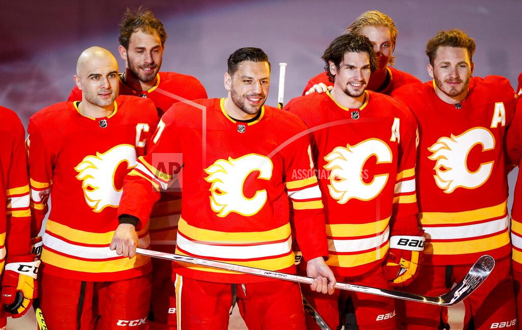 Jeff Mcintosh Calgary Flames' Milan Lucic, center, holds a silver stick as he poses with his teammates celebrating his 1000th NHL game before facing the Ottawa Senators, in Calgary, Alberta, Monday, April 19, 2021. (Jeff McIntosh/The Canadian Press via AP)