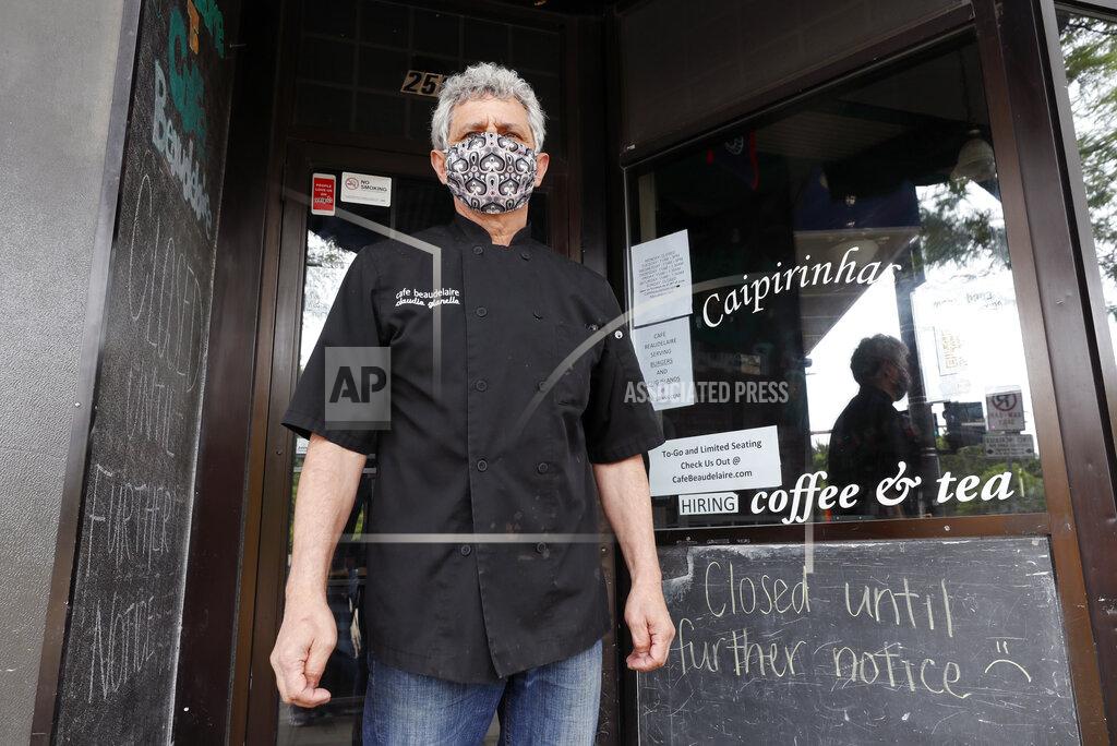 Charlie Neibergall Owner Claudio Gianello stands in the doorway of his temporarily closed Café Beaudelaire restaurant, Tuesday, June 23, 2020, in Ames, Iowa. Within a few weeks of Gov. Kim Reynolds opening bars and restaurants to customers again two major college cities in Iowa are seeing spikes in coronavirus cases among young adults between 19 and 25, reflecting similar trends seen in other states including Florida and Texas. In Ames the surge is serious enough to prompt several owners of restaurants and bars near the Iowa State University campus to close voluntarily just weeks after reopening. (AP Photo/Charlie Neibergall)