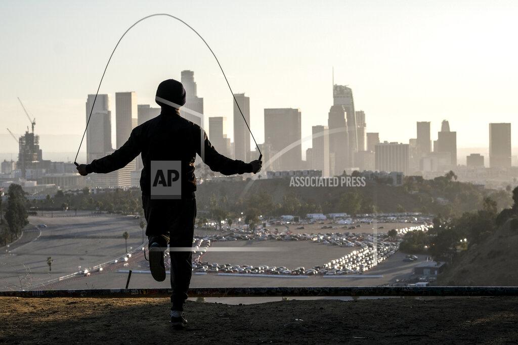 Ringo H.w. Chiu Alex Gonzalez, 19, jumps rope on Angel's Point at Elysian Park as motorists wait in long lines to take a coronavirus test in a parking lot at Dodger Stadium, Monday, Jan. 4, 2021, in Los Angeles. (AP Photo/Ringo H.W. Chiu)