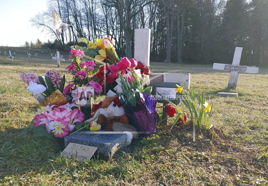Kelly Monitz Phil Jeffries, retired funeral director and deputy coroner for Carbon County, Pa., placed a marker behind the flowers on the right, on Beth Doe and her baby’s grave with their true identities, Evelyn and Emily Grace Colon, after more than four decades, in Laurytown Road Cemetery in Lehigh Township, Pa., Sunday, April 4, 2021. Flowers and a child's toy also adorn the grave. Colon, who was known for decades here in Northeast Pennsylvania as Beth Doe, was brutally murdered and dumped off an Interstate 80 bridge in East Side borough in December 1976. (Kelly Monitz/Standard-Speaker via AP)
