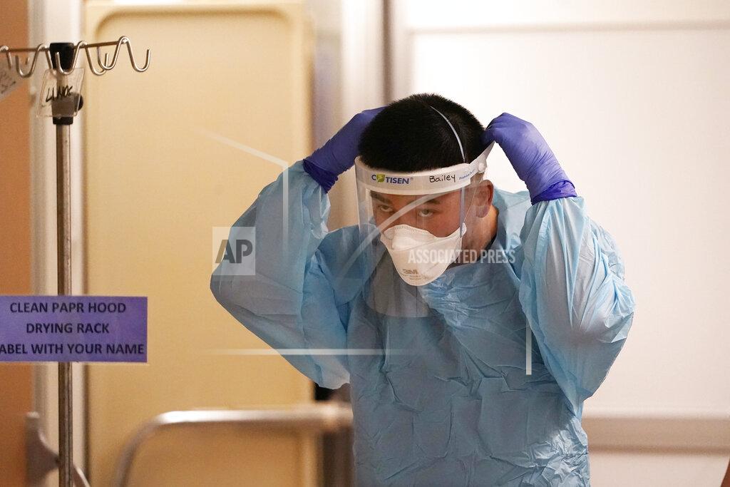 Elaine Thompson Respiratory therapist Bailey Synhavong finishes putting on protective equipment before heading into a patient's room in the COVID intensive care unit at UW Medical Center-Montlake, Tuesday, Jan. 26, 2021, in Seattle. King County, where the hospital is located, has been on a downward trend of COVID-19 cases after two-and-a-half straight months of increases. But the current lull could be, and some experts believe will be, upended as more contagious variants of the virus spread throughout United States. (AP Photo/Elaine Thompson)