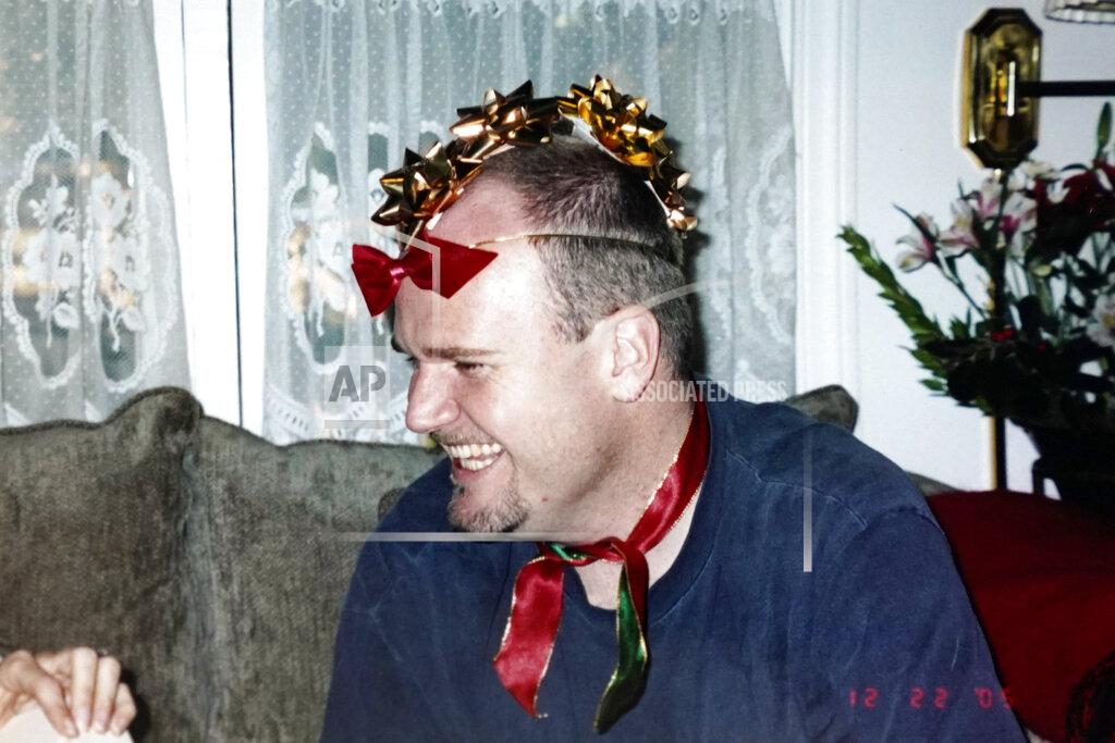 Uncredited In this Dec. 2005 photo provided by Kathleen McIlvain of Charles McIlvain, he laughs while wearing a "bow hawk" made of gift wrap bows on his head at a Christmas family gathering. Charles McIlvain was one of 34 people killed when the dive boat Conception caught fire and sank off the coast of California on Sept. 2, 2019. (Kathleen McIlvain via AP)