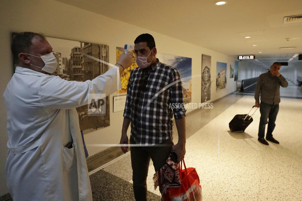 Hassan Ammar FILE - In this March 9, 2020 file photo, a passenger has his temperature checked as a precaution against a new coronavirus upon his arrival at the Rafik Hariri International Airport in Beirut, Lebanon. On Wednesday, July 1, 2020, Beirut's airport is partially reopening after a three-month shutdown and Lebanon's cash-strapped government hopes thousands of Lebanese expatriates will return for the summer, injecting badly needed dollars into the sinking economy. (AP Photo/Hassan Ammar, File)