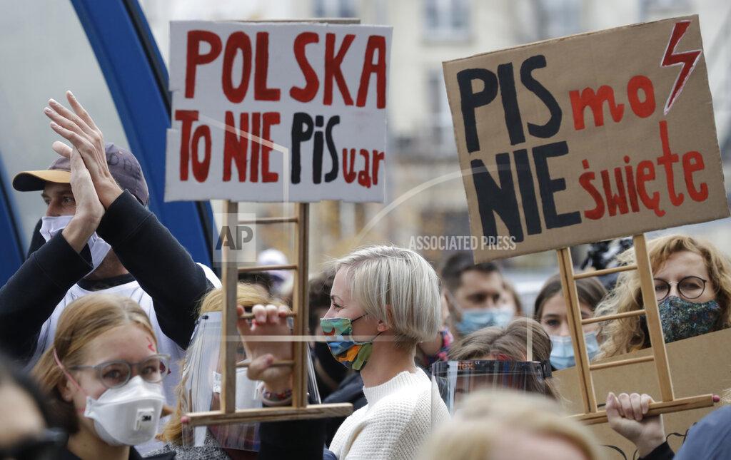 Czarek Sokolowski Women's rights activists hold placards protest against recent tightening of Poland's restrictive abortion law in front of the parliament building as inside, guards had to be used to shield right-wing ruling party leader Jaroslaw Kaczynski from angry opposition lawmakers, in Warsaw, Poland, Wednesday, Oct. 28, 2020. Massive nationwide protests have been held ever since a top court ruled Thursday that abortions due to fetal congenital defects are unconstitutional.(AP Photo/Czarek Sokolowski)