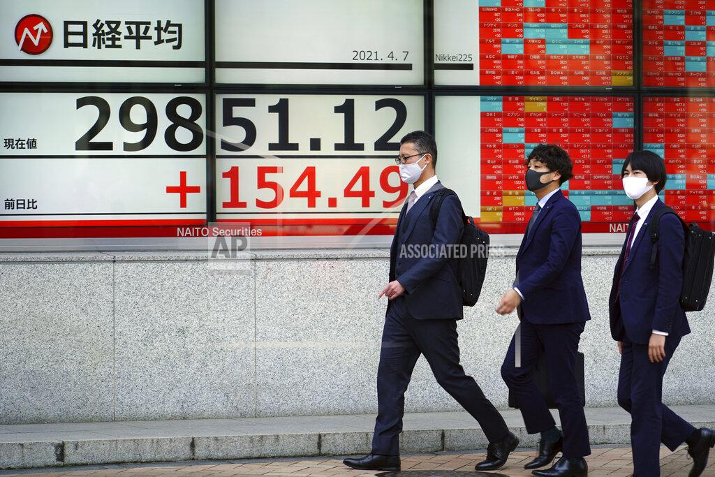 Eugene Hoshiko Men wearing protective masks walk in front of an electronic stock board showing Japan's Nikkei 225 index at a securities firm Wednesday, April 7, 2021, in Tokyo. Asian shares were mixed Wednesday after Wall Street took a breather, with major indexes edging lower. (AP Photo/Eugene Hoshiko)