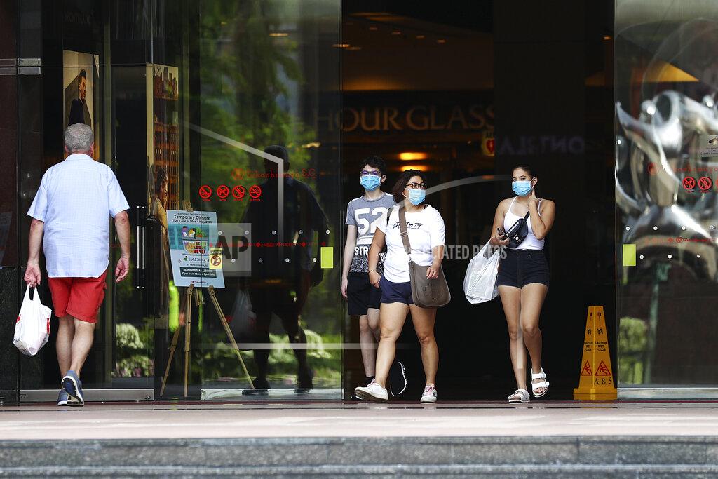 Yong Teck Lim FILE - In this April 10, 2020, file photo, people wearing protective face masks exit a mall along the Orchard Road shopping belt in Singapore. A second wave of coronavirus infections in tightly packed foreign workers' dormitories has caught Singapore off guard, and exposed the danger of overlooking marginal groups in a health crisis. Infections in Singapore, an affluent Southeast Asian city-state of fewer than 6 million people, have jumped more than a hundredfold in two months — from 226 in mid-March to over 23,000, the most in Asia after China and India.(AP Photo/Yong Teck Lim, File)