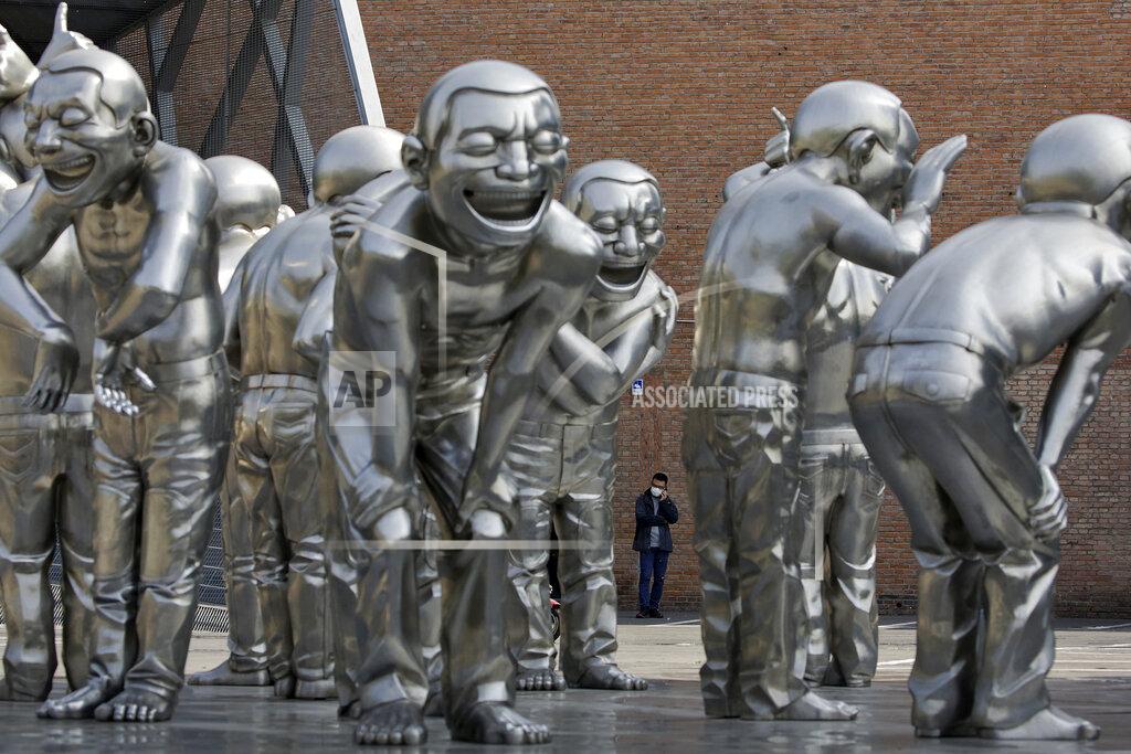 Andy Wong A man wearing a protective face mask to help curb the spread of the new coronavirus talks on his phone near the human sculptures on display outside an art gallery in Beijing, Tuesday, April 28, 2020. The Chinese city of Wuhan that was the original epicenter of the pandemic again reported no new coronavirus cases or deaths Tuesday and its hospitals remained empty of virus patients for a second straight day. (AP Photo/Andy Wong)