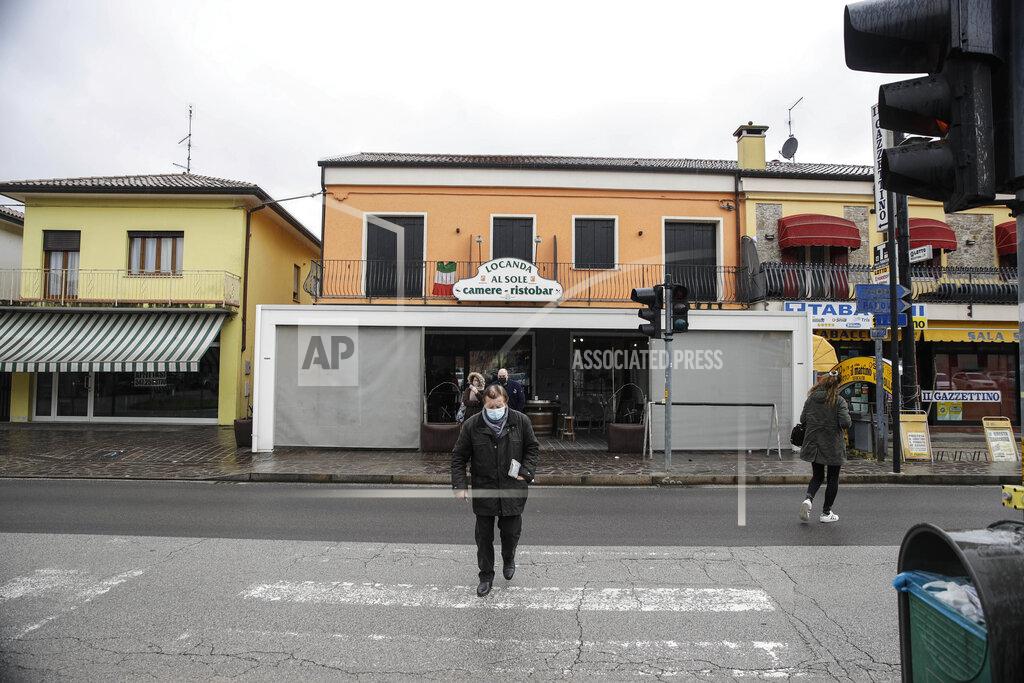 Luca Bruno People walk in front of a cafè in Vo Euganeo, northern Italy, Wednesday, Feb. 10, 2021. Shockwaves ran through the wine-making village of Vo, west of Venice, as word spread last Feb. 21 that a retired roofer had died of the new coronavirus becoming the first known COVID-19 victim in the West. (AP Photo/Luca Bruno)