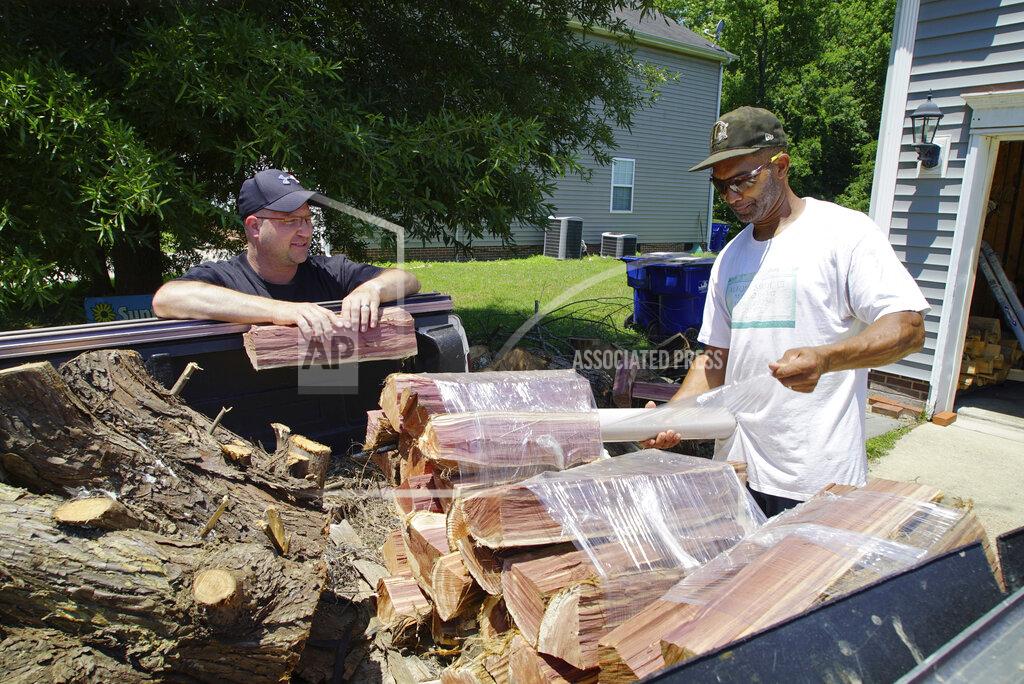 Allen G. Breed Alton Lucas, right, wraps firewood for sale as he and neighbor Ryan Isaac, a correctional officer, chat outside Lucas' home outside of Raleigh, N.C., on Friday, June 18, 2021. “I started the landscaping company, to be honest with you, because nobody would hire me because I have a felony,” said Lucas, whose business got off the ground with the help of Inmates to Entrepreneurs, a national nonprofit assisting people with criminal backgrounds by providing practical entrepreneurship education. (AP Photo/Allen G. Breed)