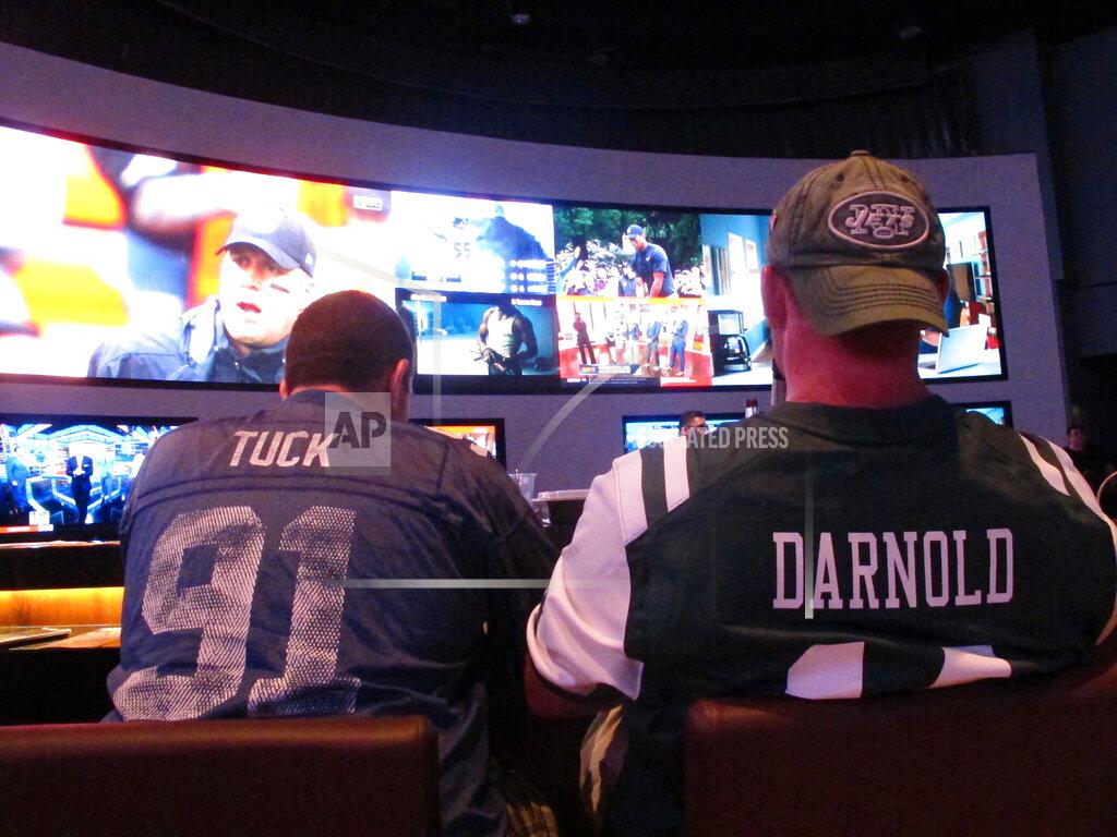 Wayne Parry FILE: This Sept. 9, 2018 file photo shows football fans waiting for kickoff in the sports betting lounge at the Ocean Casino Resort in Atlantic City, N.J. A report released Feb. 2, 2021 by the American Gaming Association predicts fewer Americans will bet on this year's Super Bowl, a decrease driven largely by fewer people back at work in offices where betting pools are circulated. But the report also predicts a record amount will be wagered online this year. (AP Photo/Wayne Parry, FILE)