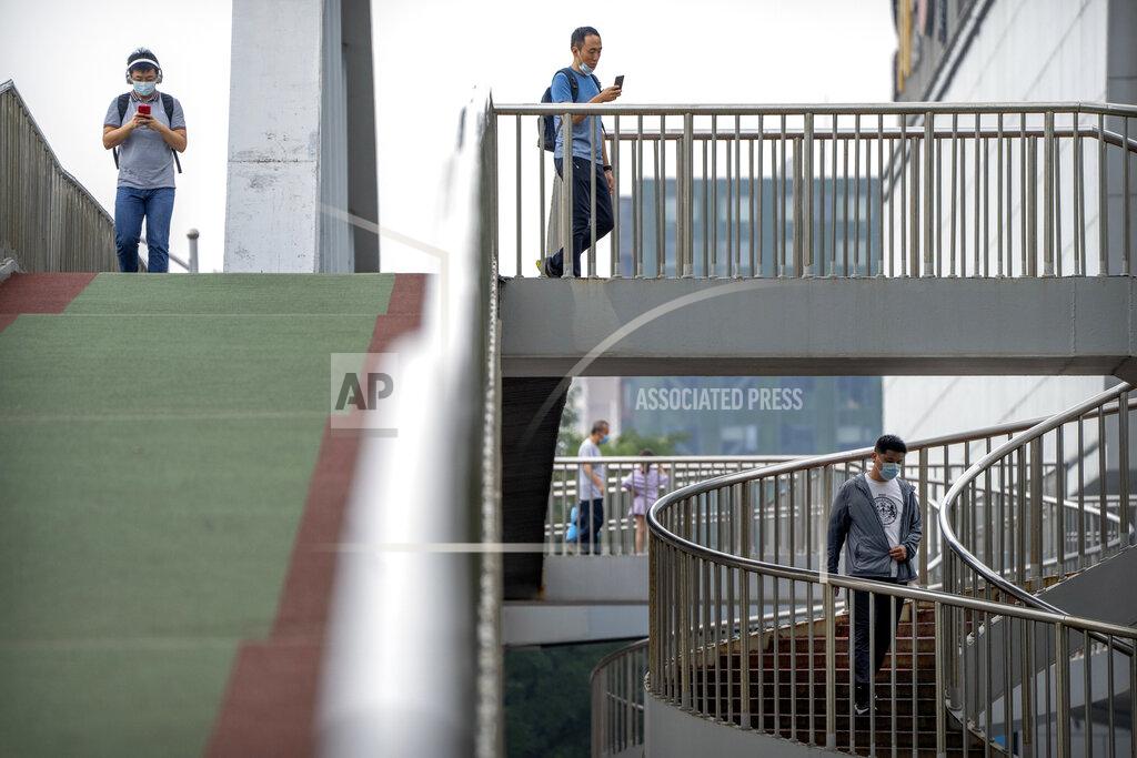 Mark Schiefelbein People wearing face masks to protect against COVID-19 walk across a pedestrian bridge during the morning rush hour in Beijing, Wednesday, Aug. 4, 2021. China's worst coronavirus outbreak since the start of the pandemic a year and a half ago escalated Wednesday with dozens more cases around the country, the sealing-off of one city and the punishment of its local leaders. (AP Photo/Mark Schiefelbein)