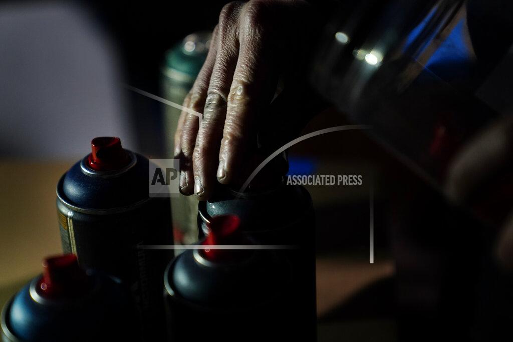 Brynn Anderson Artist Brandon Litman reaches for a can of spray paint before making a campaign poster for voters, after Georgia's Senate runoff race on Saturday, Jan. 9, 2021, in Atlanta. (AP Photo/Brynn Anderson)