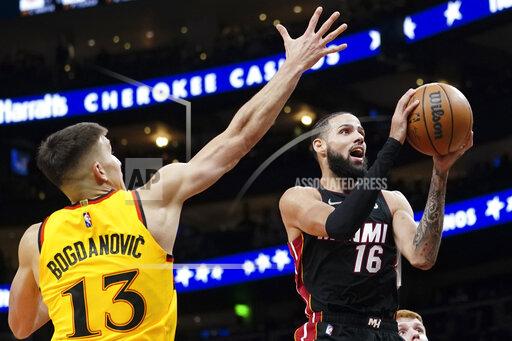 Miami Heat forward Caleb Martin (16) shoots as Atlanta Hawks guard Bogdan Bogdanovic (13) defends during the second half of an NBA basketball game Wednesday, Jan. 12, 2022, in Atlanta. (AP Photo/John Bazemore)
