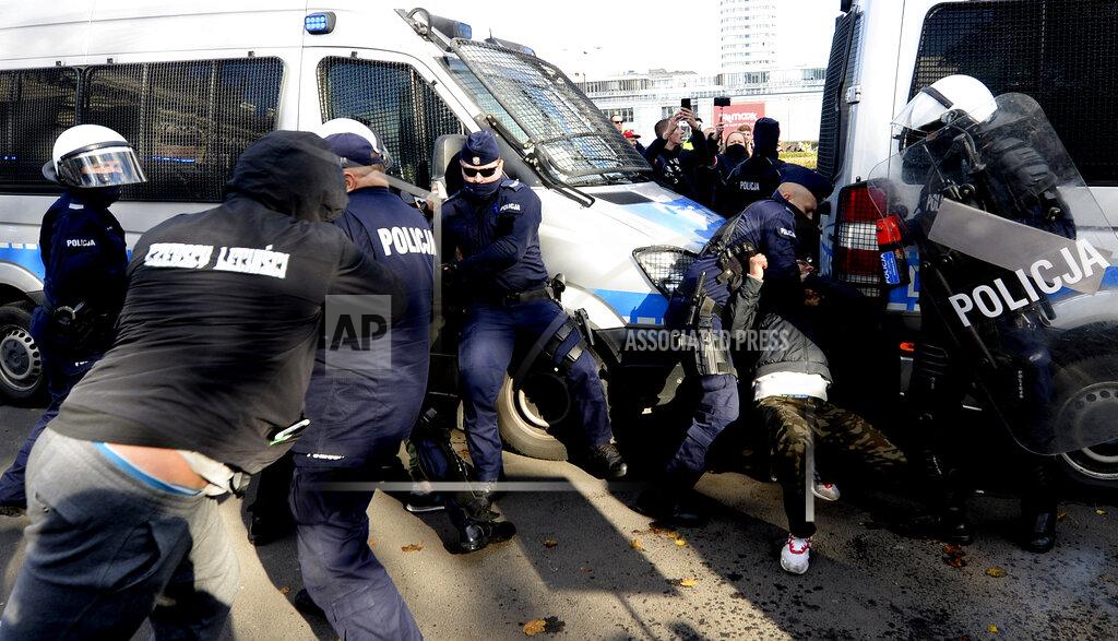 Polish police aim tear gas cannisters at protesters angry over new restrictions aimed at fighting the coronavirus pandemic, in Warsaw, Poland, Saturday, Oct. 24, 2020. The protesters included entrepreneurs, far-right politicians, football fans and vaccine opponents. The protesters, many wearing no protective masks, violated a new restriction on gatherings of more people. The clashes come amid rising social tensions and as new restrictions just short of a full lockdown took effect Saturday. (AP Photo/Czarek Sokolowski)