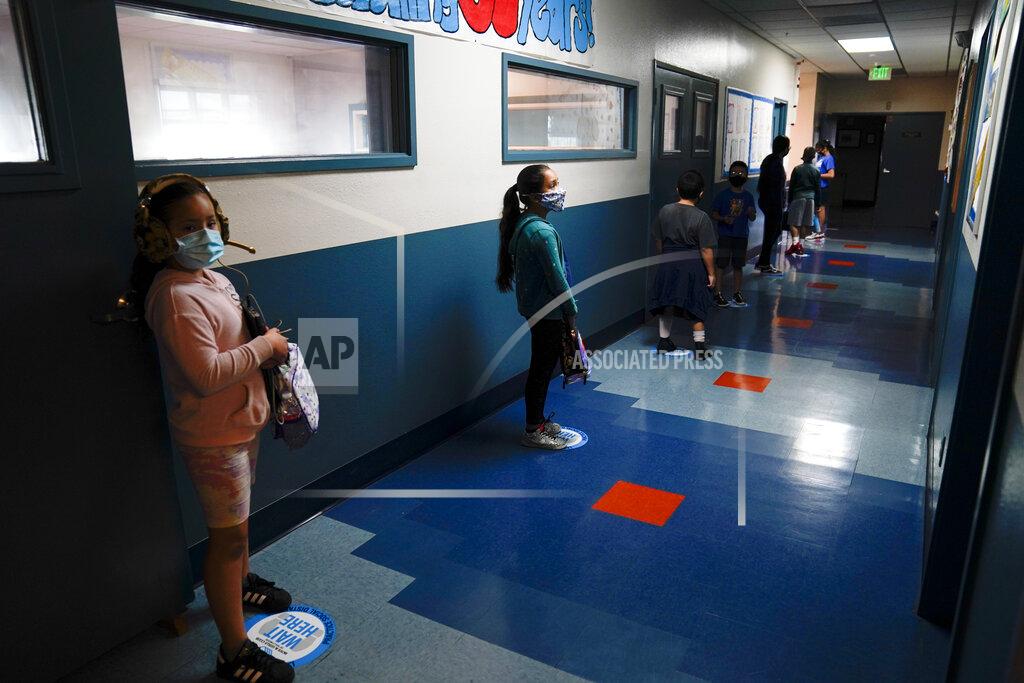Jae C. Hong Los Angeles Unified School District students stand in a hallway socially distance during a lunch break at Boys & Girls Club of Hollywood in Los Angeles, Wednesday, Aug. 26, 2020. The LAUSD schools resumed classes with distance learning, but many underprivileged students still struggle, according to Mel Culpepper, CEO of Boys & Girls Club of Hollywood. The facility is open for children whose parents must leave home to work. There is no charge. Snacks and lunch are provided. "These kids are already behind," said Culpepper. "Our mission is to help the kids and families that need us most and that's what we are doing." (AP Photo/Jae C. Hong)