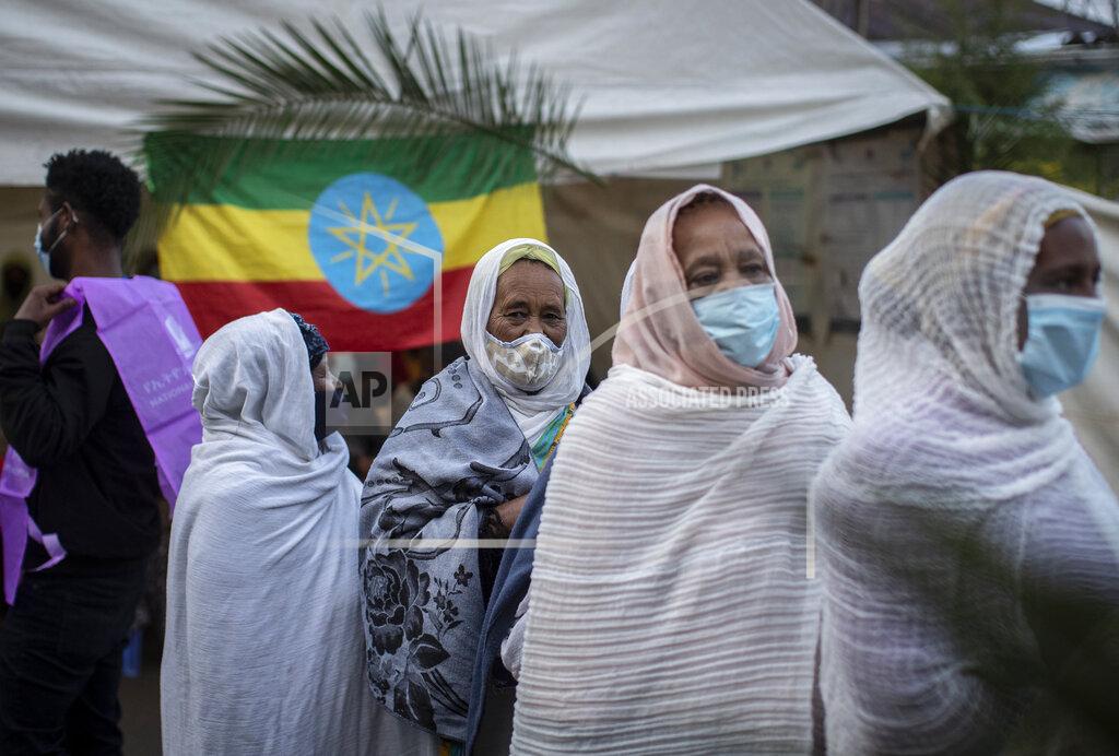 Ben Curtis Ethiopians queue to cast their votes in the general election, next to a national flag, at a polling center in the capital Addis Ababa, Ethiopia, Monday, June 21, 2021. Ethiopia was voting Monday in the greatest electoral test yet for Prime Minister Abiy Ahmed as insecurity and logistical issues meant ballots wouldn't be cast in more than 100 constituencies of the 547 across the country. (AP Photo/Ben Curtis)