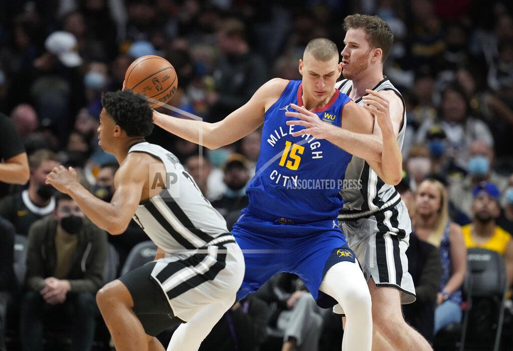David Zalubowski Denver Nuggets center Nikola Jokic, center, drives between San Antonio Spurs forward Keldon Johnson, front, and center Jakob Poeltl during the first half of an NBA basketball game Friday, Oct. 22, 2021, in Denver. (AP Photo/David Zalubowski)