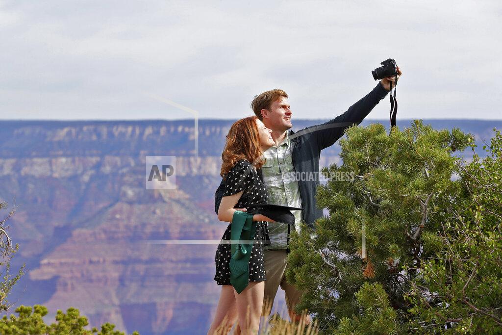 Matt York Recent Baylor University graduate Cady Malachowski takes a photo with Andrew Fink at the Grand Canyon Friday, May 15, 2020, in Grand Canyon, Ariz. Tourists are once again roaming portions of Grand Canyon National Park when it partially reopened Friday morning, despite objections that the action could exacerbate the coronavirus pandemic.. (AP Photo/Matt York)