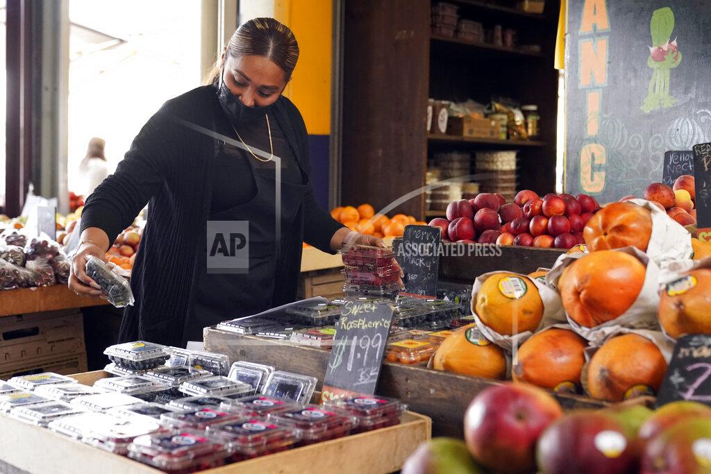 Marcio Jose Sanchez A worker wears a mask while setting up a fruit display amid the COVID-19 pandemic Thursday, May 20, 2021, at The Farmers' Market in Los Angeles. California regulators will shoot for a mid-June easing of workplace masking and social distancing requirements to conform with a broader state order. They asked to delay a debate Thursday on how quickly they should drop coronavirus safety rules for employees. (AP Photo/Marcio Jose Sanchez)