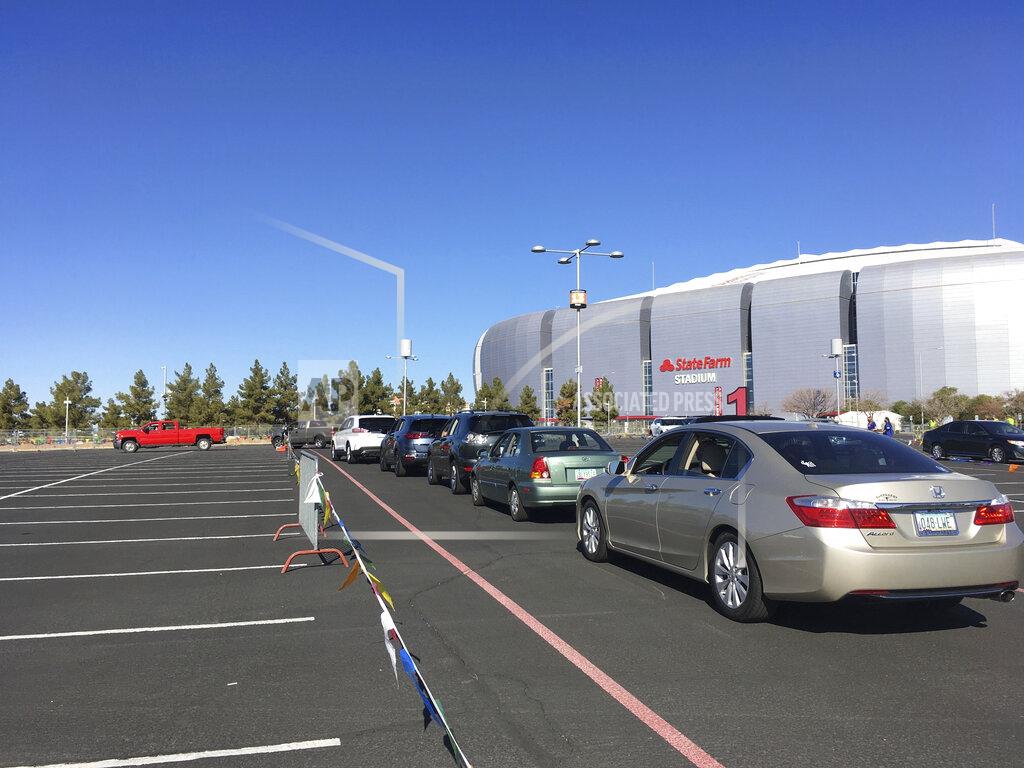 Terry Tang Drivers wait in line to get the COVID-19 vaccine in the parking lot of the State Farm Stadium in Glendale, Ariz., on Monday, Jan. 11, 2021. The Arizona Cardinals' stadium opened as a vaccination site Monday that will be a 24-7 operation. (AP Photo/Terry Tang)