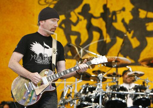 FILE - U2 guitarist The Edge wears a Music First T-shirt as he performs during the New Orleans Jazz and Heritage Festival in New Orleans on April 29, 2006. The Edge and his Music Rising charity will host an auction of rock memorabilia on Dec. 11, 2021 to benefit New Orleans musicians hit hard by the pandemic. Items for sale include what Edge calls his “One” guitar and memorabilia from Alice Cooper and Aerosmith to Pink Floyd and Kiss. (AP Photo/Alex Brandon, File)
