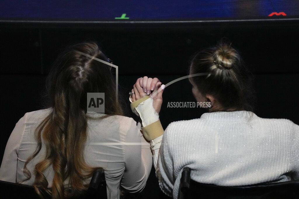 Rebecca Blackwell Angela Gonzalez, right, holds hands with her daughter Deven, as both sit in wheelchairs due to their injuries during the funeral service for their late husband and father Edgar Gonzalez, 44, who was killed last month in the Champlain Towers South condominium collapse, on Friday, July 23, 2021, at Christ Fellowship church in Palmetto Bay, Fla. Angela and Deven were injured but survived the collapse, falling multiple stories.(AP Photo/Rebecca Blackwell)
