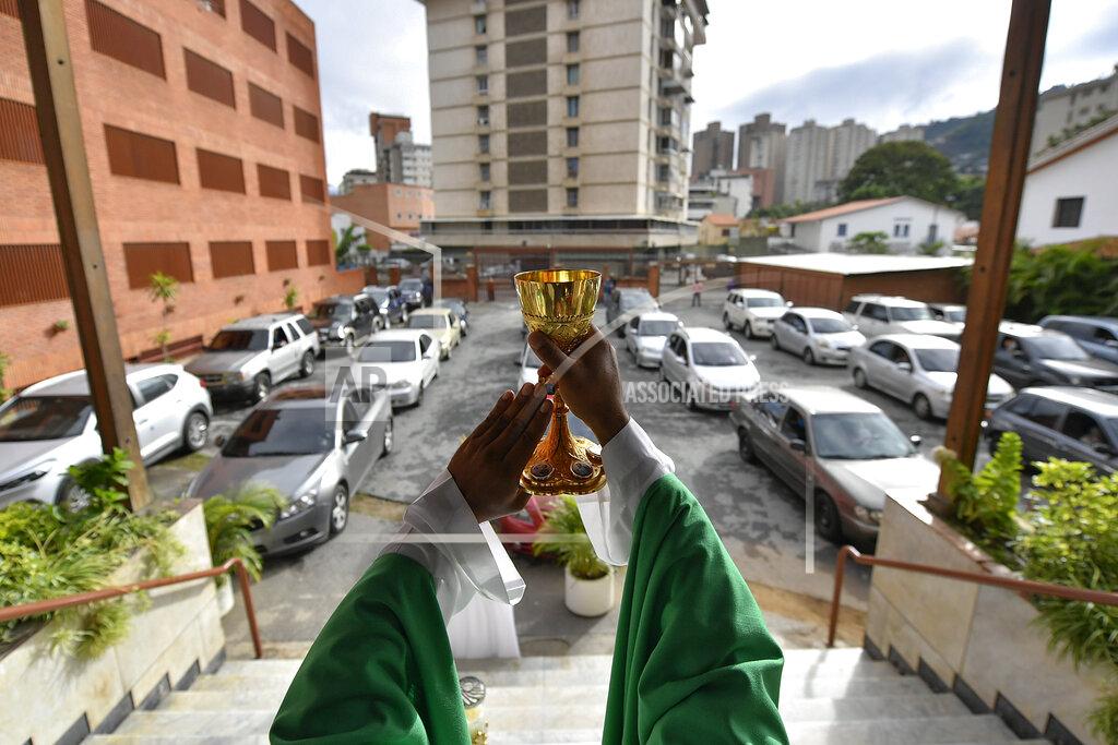 Matias Delacroix Father Jonathan Gonzalez celebrates a drive-in Sunday Mass set up to circumvent the regulations that prevent concentrations in religious temples, imposed since March by the authorities to curb the spread of the new coronavirus, at the parking lot of the "Nuestra Señora de Coromoto" church in the El Paraiso neighborhood of Caracas, Venezuela, Sunday, Oct. 25, 2020. (AP Photo/Matias Delacroix)