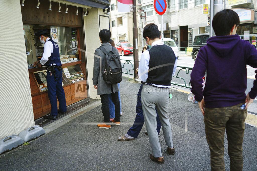 Eugene Hoshiko FILE - In this April 22, 2020, file photo, people wearing masks to protect themselves against the spread of the new coronavirus queue up to buy lunch at a shop in Tokyo. Under Japan's coronavirus state of emergency, people have been asked to stay home. Many are not. Some still have to commute to their jobs despite risks of infection, while others are dining out, picnicking in parks and crowding into grocery stores with scant regard for social distancing. (AP Photo/Eugene Hoshiko, File)